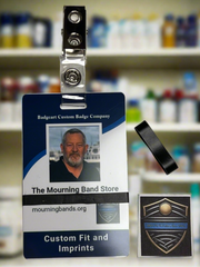 A photo of a blue employee identification badge for Badgeart Custom Badge Co. with a black silicone mourning band attached. An unattached band is shown next to the badge, demonstrating how to wear a mourning band on a public safety civilian employee ID to mourn a coworker's death.