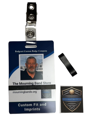 A photo of a blue employee identification badge for Badgeart Custom Badge Co. with a black silicone mourning band attached. An unattached band is shown next to the badge, demonstrating how to wear a mourning band on a public safety civilian employee ID to mourn a coworker's death.