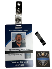 A photo of a blue employee identification badge for Badgeart Custom Badge Co. with a black silicone mourning band attached. An unattached band is shown next to the badge, demonstrating how to wear a mourning band on a public safety civilian employee ID to mourn a coworker's death.