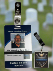 A photo of a blue employee identification badge for Badgeart Custom Badge Co. with a black silicone mourning band attached. An unattached band is shown next to the badge, demonstrating how to wear a mourning band on a public safety civilian employee ID to mourn a coworker's death.