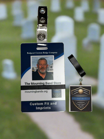 A photo of a blue employee identification badge for Badgeart Custom Badge Co. with a black silicone mourning band attached. An unattached band is shown next to the badge, demonstrating how to wear a mourning band on a public safety civilian employee ID to mourn a coworker's death.