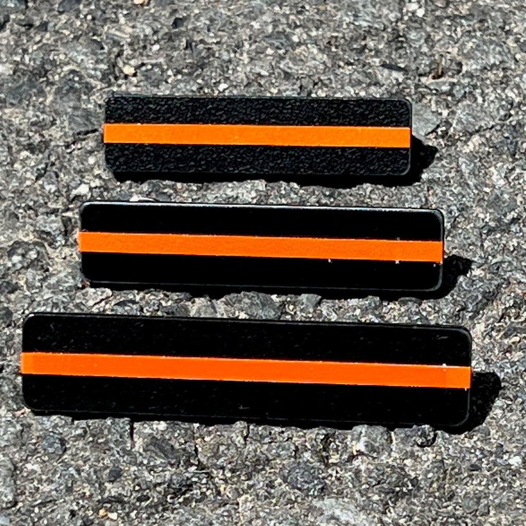 The Stop Gun Violence Wear Orange Awareness / Thin Orange Line Mourning Bars for Cloth Badges and insignia.  Black vinyl with a thin orange line mourning bar with a pair of 1/2" pins with military clasps.  Public safety officers are wearing thin orange line badge shrouds to raise awareness of gun violence in the community and among police officers, firefighters, Emergency Medical Services and others.  J